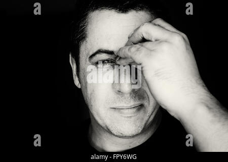 Close up head portrait of a middle aged young looking male in black and white monochrome. The man holds his nose and sinus area Stock Photo