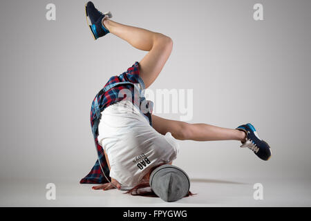 One fit young woman wearing casual plaid shirt performing breakdance moves on the floor. Modern style beautiful teen dancer work Stock Photo