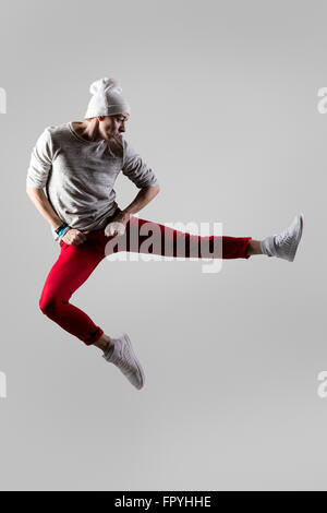 One young attractive modern style dancer guy in casual red jeans working out, dancing and jumping in mid-air. Full length photo Stock Photo
