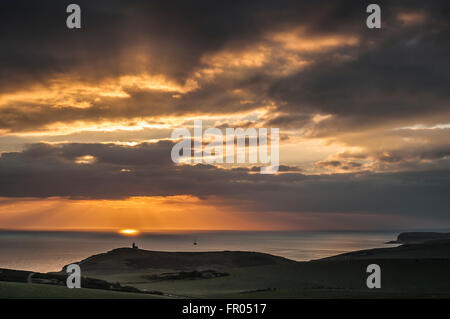 Eastbourne, East Sussex, UK..20 March 2016..Glorious end to the Day as the Sun sets beyond the clouds over Belle Tout Lighthouse. Stock Photo