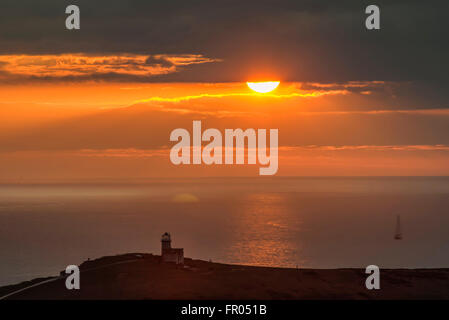 Eastbourne, East Sussex, UK..20 March 2016..Glorious end to the Day as the Sun sets beyond the clouds over Belle Tout Lighthouse. Stock Photo