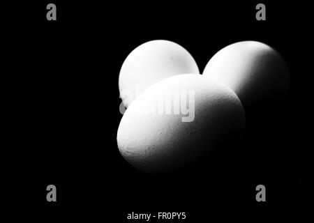 Three eggs against a dark black background with copyspace area. Stock Photo