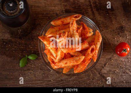 Penne pasta in tomato sauce with meat and tomatoes on a wooden background Stock Photo