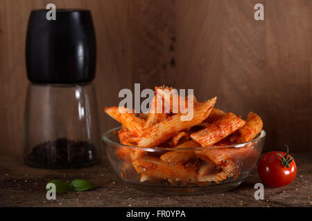 Penne pasta in tomato sauce with meat and tomatoes on a wooden background Stock Photo