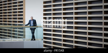 Senior businessman standing on walkway in modern office Stock Photo