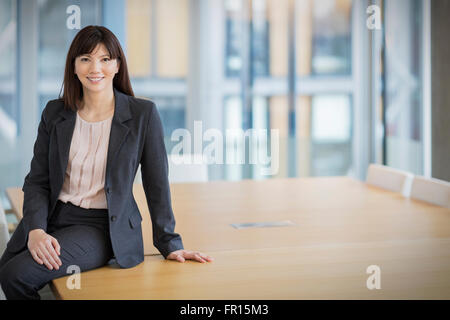 Portrait smiling businesswoman leaning on conference table Stock Photo