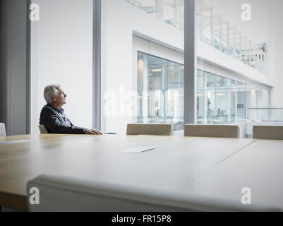 Pensive senior businessman looking out conference room window Stock Photo