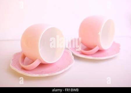Two delicate matching pink ceramic cups with white interiors and decorative saucers creating a soft, feminine aesthetic, evoking concepts of tea time Stock Photo