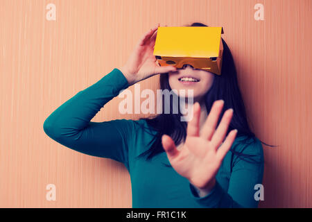 Attractive young girl playing video game with cardboard virtual reality headset. Trending technology and hipster colors. Stock Photo