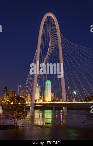 Dallas Skyline with Margaret Hunt Hill Bridge in Foreground, clear blue sky and reflection in Trinity river flood waters. Sunset Stock Photo