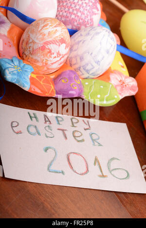 Easter with eggs in nest and yellow tulips over wooden table. Stock Photo
