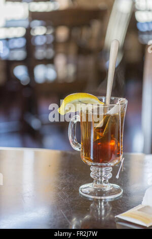 A hot cup of tea with a lemon on the side and tea bag inside as heat rises Stock Photo