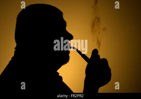 Outline portrait of caucasian bearded man smoking tobacco pipe against sepia background Stock Photo