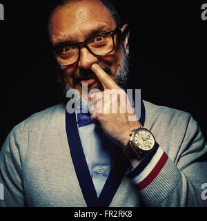 Funny portrait of a middle age man, holding a finger in his nose. Stock Photo
