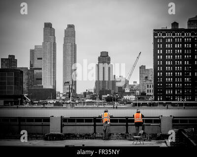 Two Workers on construction site having a break and looking over railings, New York city, USA. Stock Photo
