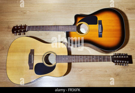 two acoustic guitars lying on wooden floor closeup Stock Photo