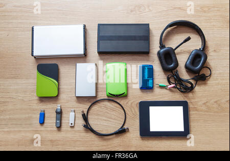 set of hard drives, memory cards, card reader, tablet, phones lying on wooden floor closeup Stock Photo