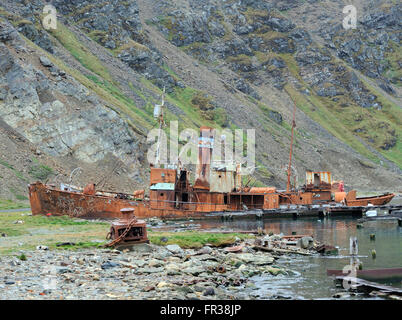 A whaling boat  beached in the ruins of the Grytviken whaling station and a view of King Edward Cove. Grytviken, South Georgia Stock Photo