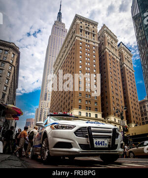 NYPD patrol car with Empire State Building seen from W 34th St, New York City, USA. Stock Photo