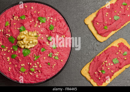Beet hummus in a black bowl and two slices of bread with beet hummus on a slate plate Stock Photo