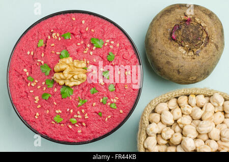 Beet hummus in a black bowl, chickpeas and a fresh beet on blue background Stock Photo