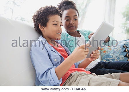 preteen brother and sister playing on pc tablet together