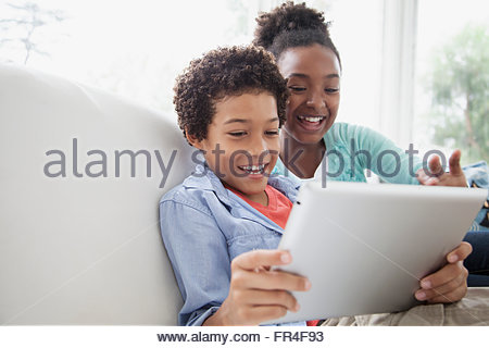 sister and brother laughing while playing on pc tablet