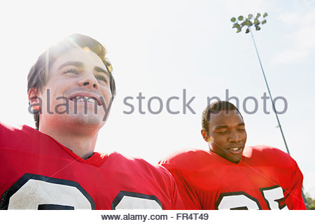 Smiling group of young American football players walking onto a grassy  field together on a sunny afternoon during a football game Stock Photo -  Alamy