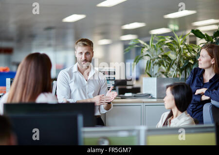 Businessman leading meeting in office cubicle Stock Photo