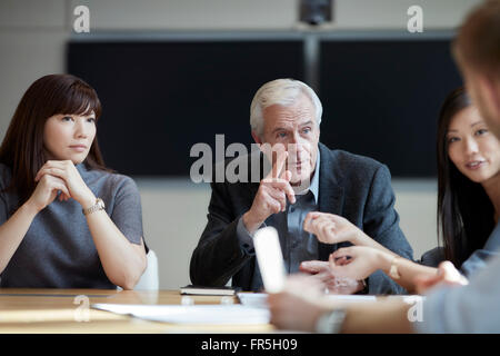 Senior businessman gesturing and talking in meeting Stock Photo