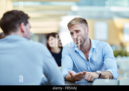 Businessman gesturing and talking to colleague Stock Photo