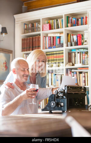 Senior couple drinking wine at typewriter Stock Photo