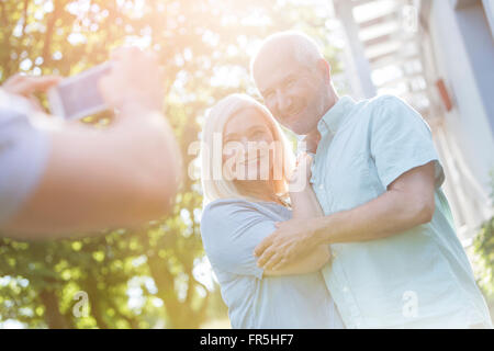 Man photographing senior couple outdoors Stock Photo
