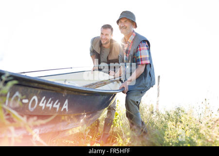 Father and adult son lifting fishing boat Stock Photo