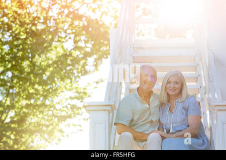 Portrait smiling senior couple sitting on summer stairs Stock Photo