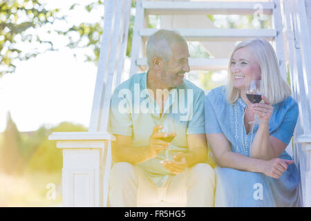 Senior couple drinking wine on summer stairs Stock Photo