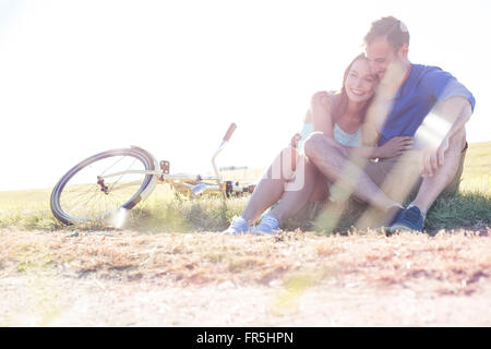 Affectionate young couple hugging near bicycle in rural grass Stock Photo