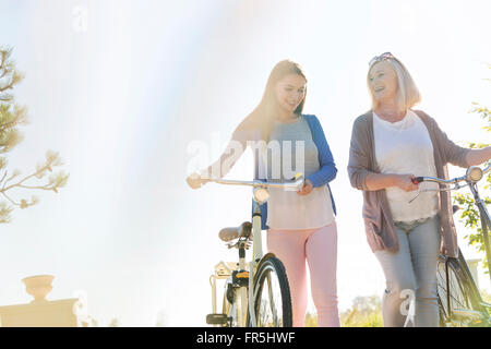 Mother and adult daughter walking bicycles Stock Photo