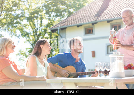 Father opening bottle of rose wine for family at sunny patio table Stock Photo