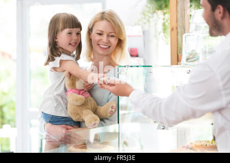 Worker giving girl cookie in bakery Stock Photo