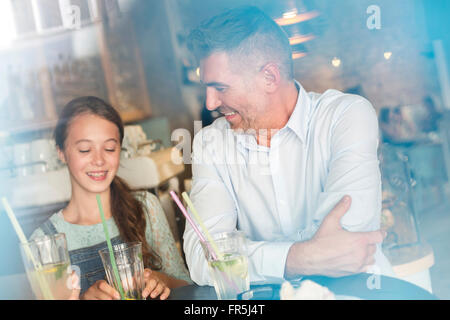 Father and daughter drinking lemonade at cafe table Stock Photo