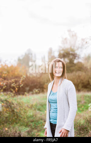 Smiling woman looking away in autumn park Stock Photo