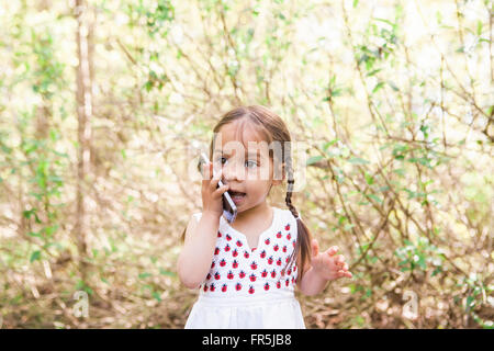 Toddler girl talking on cell phone in park Stock Photo