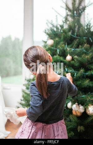 Toddler girl decorating Christmas tree Stock Photo