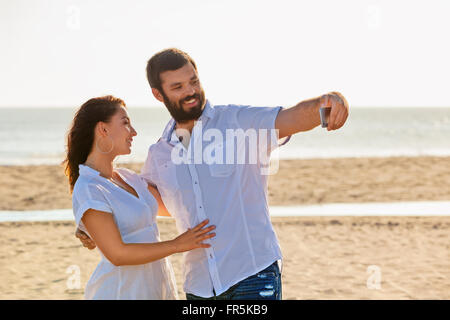 Happy family on honeymoon holidays - just married loving couple have fun and taking selfie for social network on sea beach. Life Stock Photo