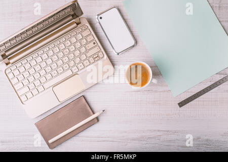 Laptop, phone and address book and a cup on a wooden table horizontal Stock Photo