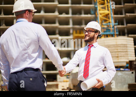 Two male architects shaking hands at construction site Stock Photo