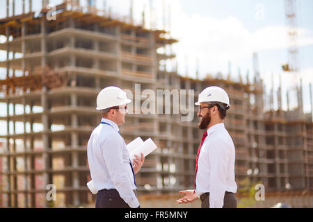 Young male engineers talking at construction site Stock Photo