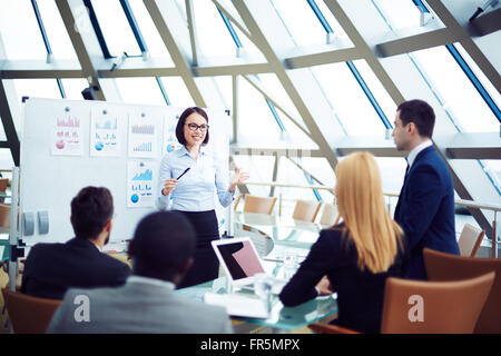 Young employee giving a presentation to business people Stock Photo
