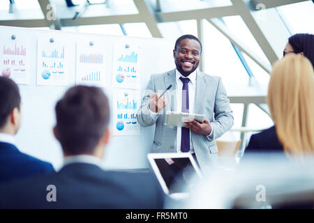 Smiling African businessman explaining project to his colleagues Stock Photo